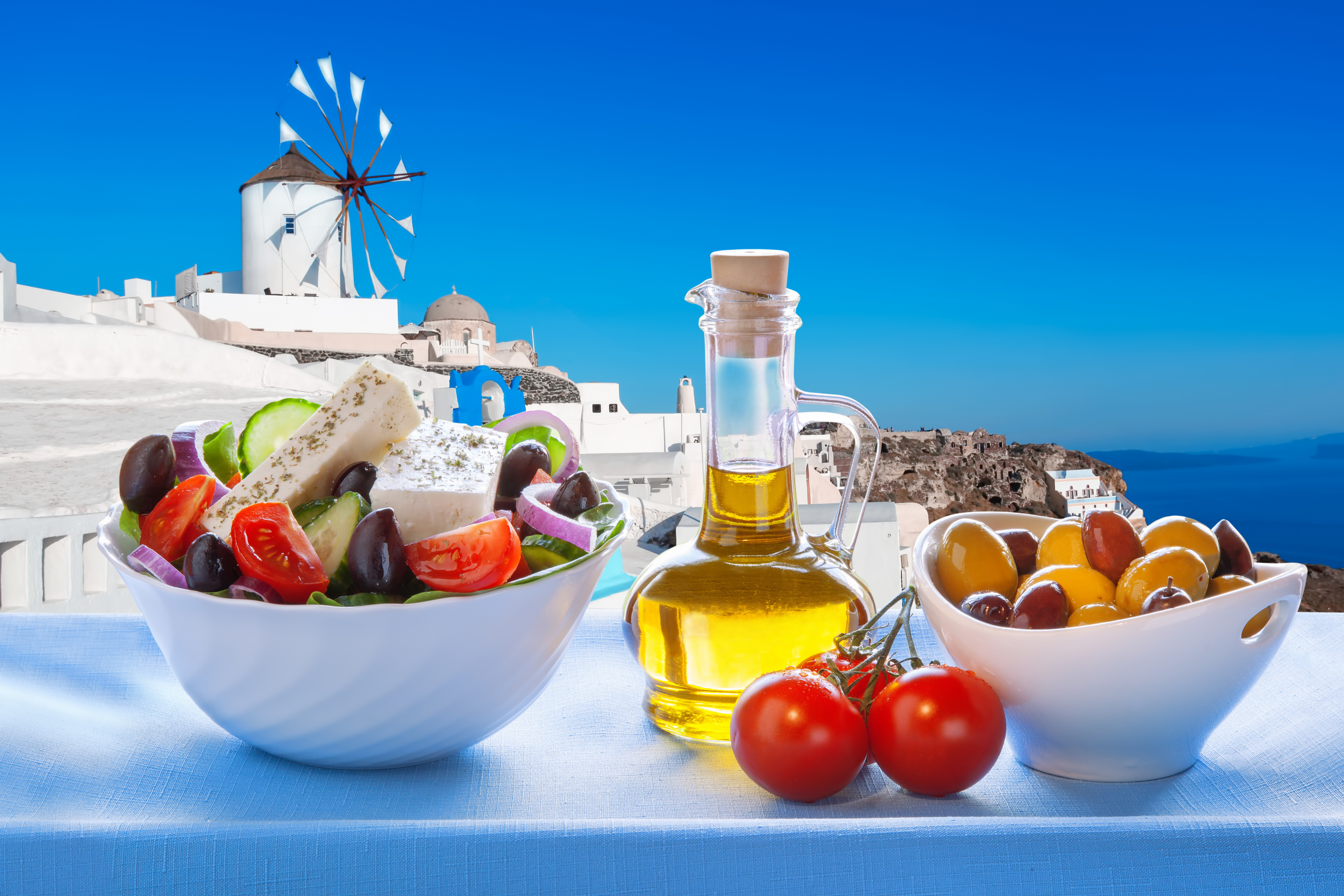 Greek salad against windmill in Oia village Santorini island in Greece_shutterstock_276817688.jpg Greek salad against windmill in Oia village Santorini island in Greece_shutterstock_276817688.jpg